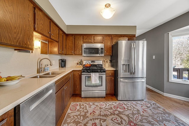 kitchen featuring brown cabinets, appliances with stainless steel finishes, light countertops, and a sink