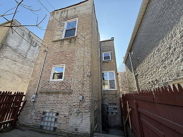 view of side of home featuring brick siding and fence