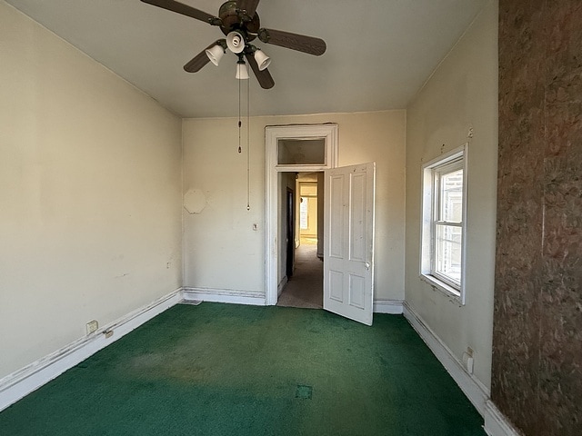 empty room with a ceiling fan, carpet, and baseboards