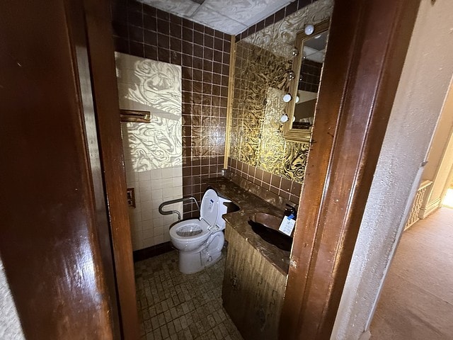 bathroom featuring toilet, tile walls, vanity, and tile patterned flooring