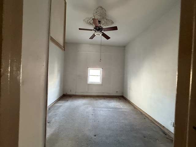 empty room with unfinished concrete floors and a ceiling fan