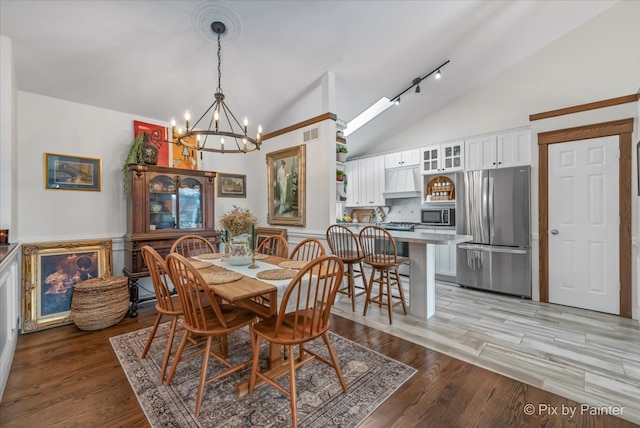 dining space featuring light wood-type flooring, visible vents, a notable chandelier, high vaulted ceiling, and rail lighting