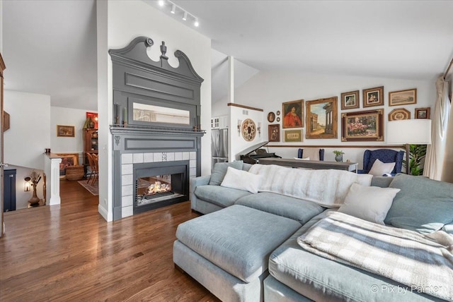 living room with a tile fireplace, wood finished floors, and vaulted ceiling