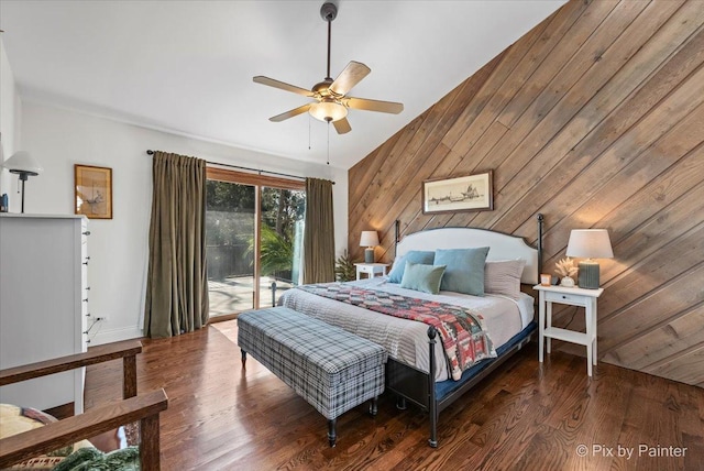 bedroom with a ceiling fan, wood finished floors, wooden walls, access to exterior, and vaulted ceiling