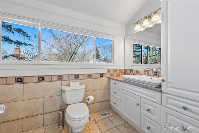 bathroom with visible vents, toilet, tile patterned flooring, vanity, and vaulted ceiling