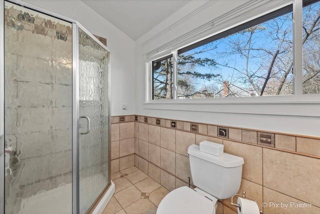 full bath featuring wainscoting, a stall shower, toilet, and tile walls