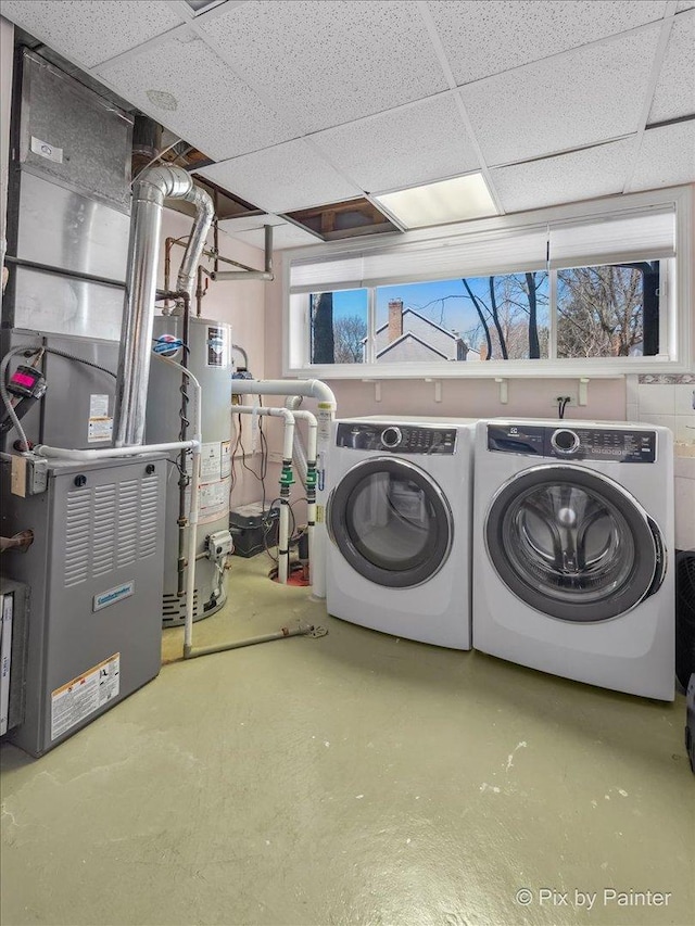 washroom featuring laundry area, heating unit, water heater, and washer and clothes dryer