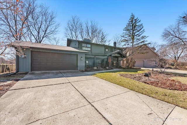 mid-century inspired home featuring an attached garage, a chimney, and driveway