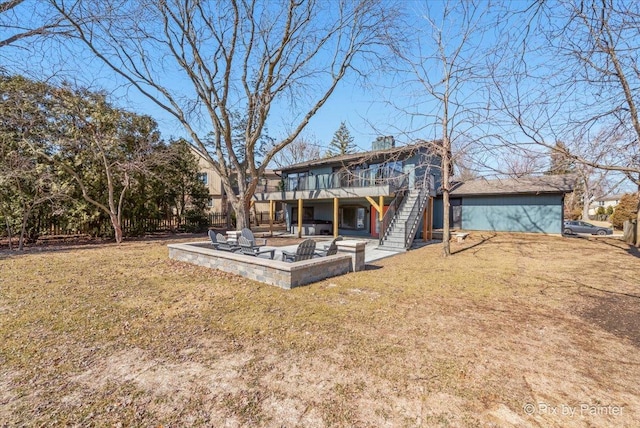 rear view of property with stairway, an outdoor fire pit, a lawn, a deck, and a patio area