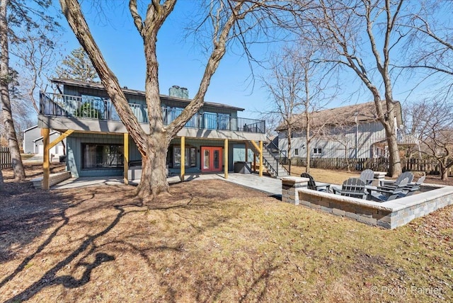 back of property featuring fence, stairway, a fire pit, a wooden deck, and a patio area