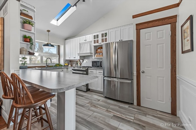 kitchen featuring premium range hood, a peninsula, stainless steel appliances, white cabinetry, and open shelves