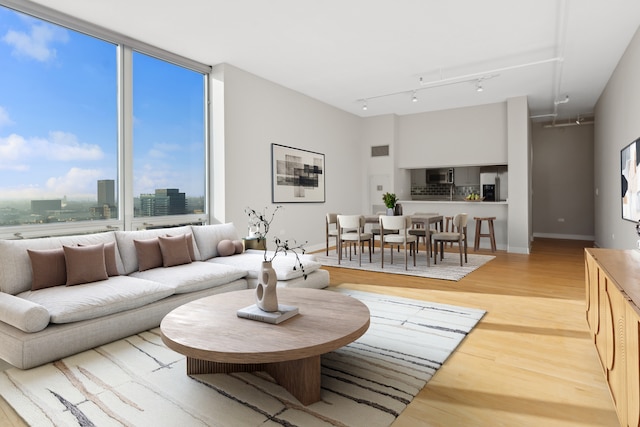 living area featuring light wood finished floors, visible vents, rail lighting, and baseboards