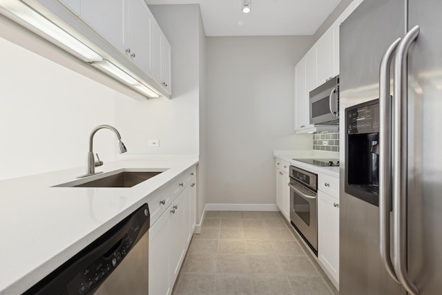 kitchen with baseboards, light countertops, white cabinets, stainless steel appliances, and a sink