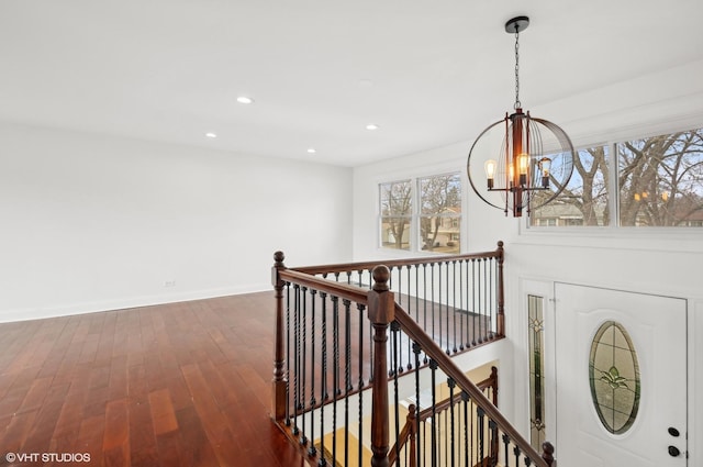 corridor featuring baseboards, an upstairs landing, recessed lighting, an inviting chandelier, and dark wood-style flooring