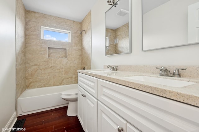 full bathroom featuring toilet, double vanity, wood finished floors,  shower combination, and a sink