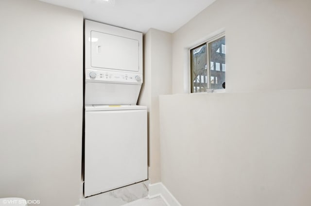 clothes washing area with laundry area, baseboards, and stacked washing maching and dryer