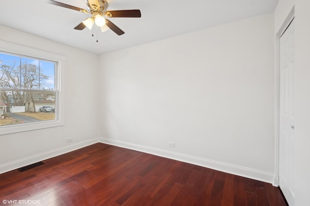 spare room with ceiling fan, dark wood-style floors, visible vents, and baseboards