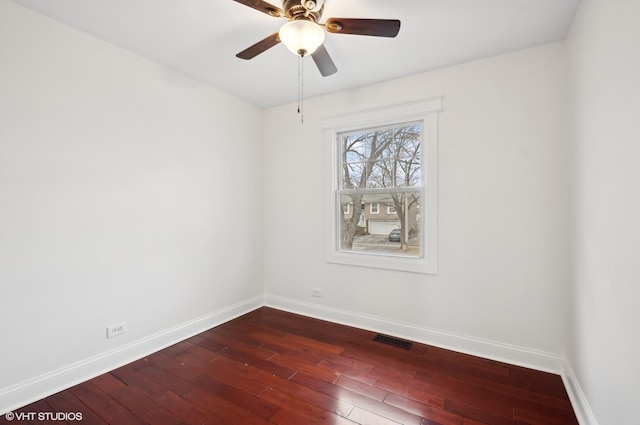 unfurnished room with a ceiling fan, dark wood-style floors, visible vents, and baseboards