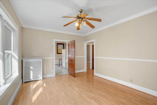 spare room with crown molding, radiator heating unit, baseboards, and wood finished floors