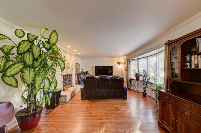 living area with recessed lighting, crown molding, a fireplace, and light wood-type flooring