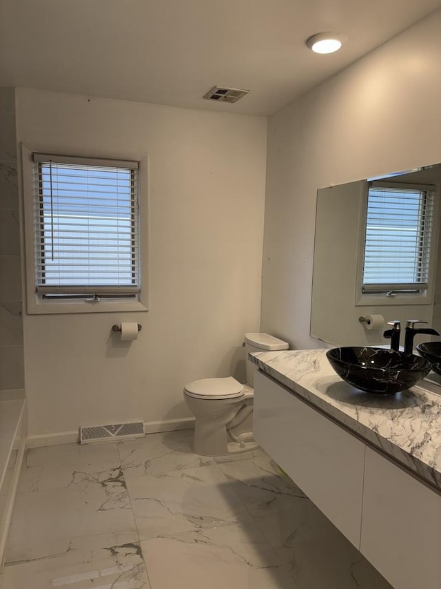 bathroom featuring toilet, baseboards, visible vents, and marble finish floor