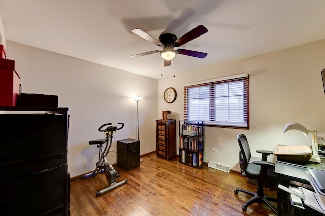 office area featuring ceiling fan, visible vents, baseboards, and wood finished floors