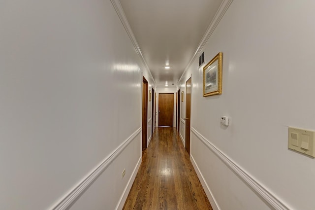 hallway featuring dark wood-type flooring, visible vents, and ornamental molding