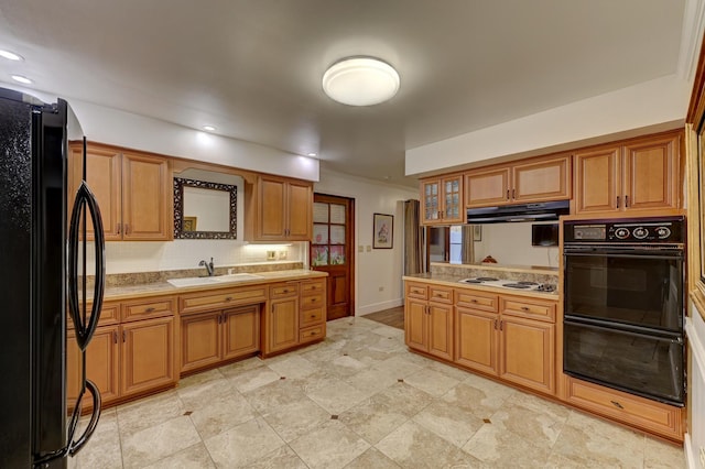 kitchen featuring brown cabinetry, black appliances, light countertops, and a sink