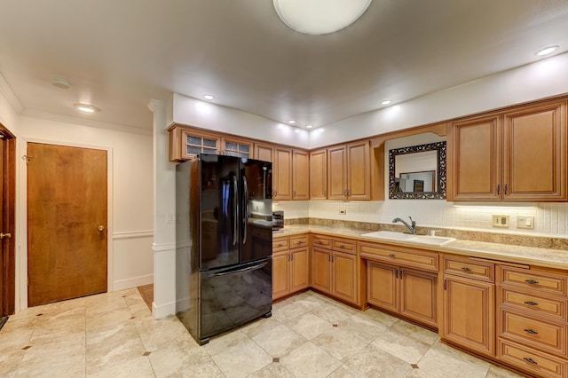 kitchen with brown cabinets, a sink, freestanding refrigerator, light countertops, and decorative backsplash