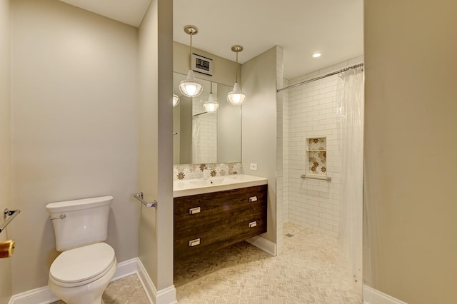 bathroom featuring baseboards, tiled shower, toilet, and vanity