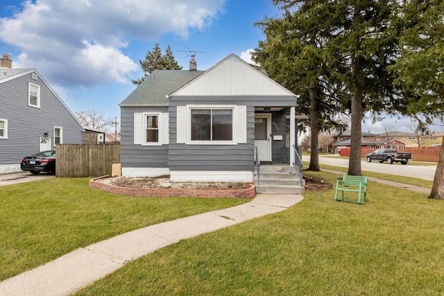 bungalow-style home with a chimney, a shingled roof, a front yard, and fence