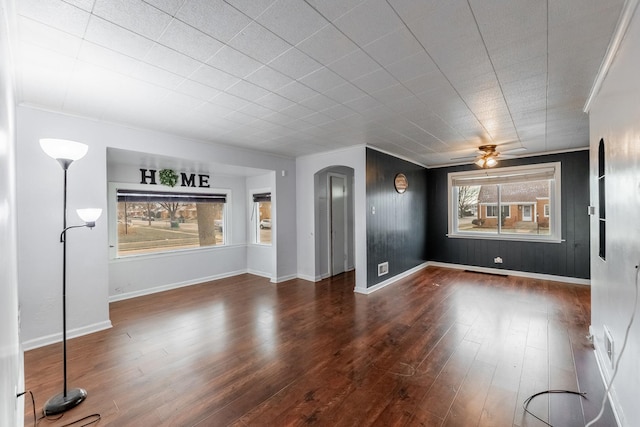 interior space with wood finished floors, arched walkways, and baseboards