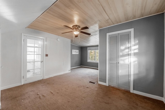 interior space featuring baseboards, visible vents, ceiling fan, wooden ceiling, and carpet flooring