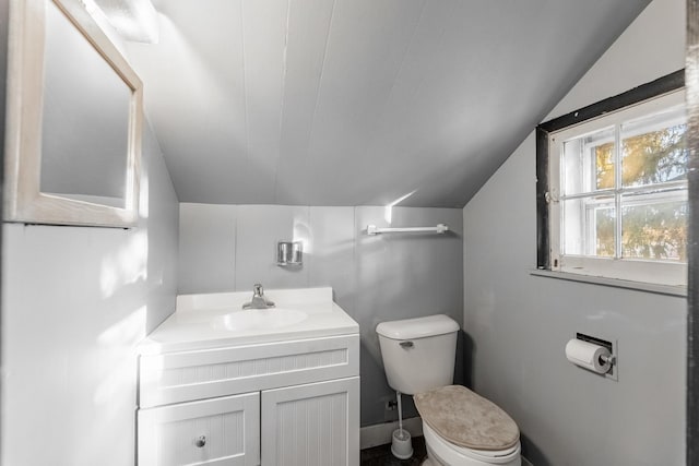 half bathroom featuring lofted ceiling, toilet, and vanity