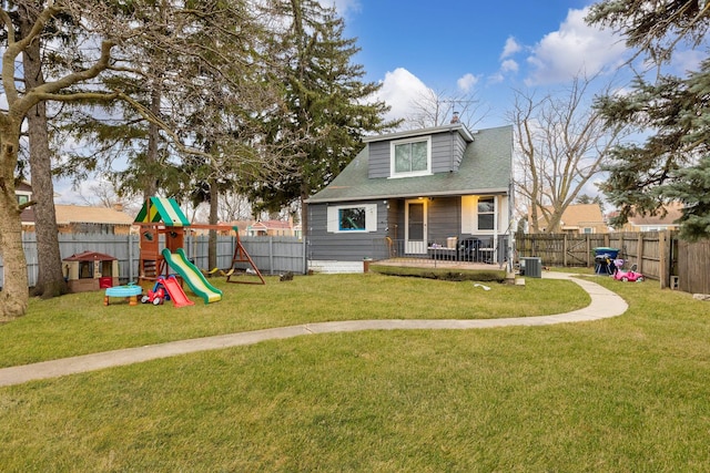 view of front of house with cooling unit, a front lawn, a playground, and a fenced backyard