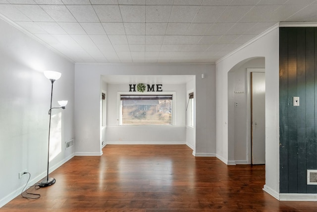 unfurnished living room with arched walkways, visible vents, ornamental molding, and wood finished floors