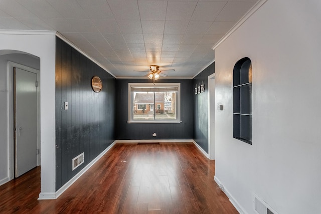 empty room featuring baseboards, wood finished floors, visible vents, and ornamental molding