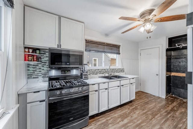 kitchen with a sink, light countertops, white cabinets, appliances with stainless steel finishes, and light wood-type flooring