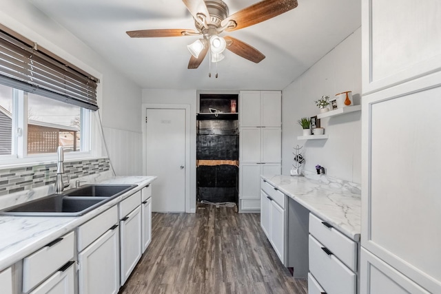 kitchen with tasteful backsplash, open shelves, dark wood finished floors, white cabinets, and a sink