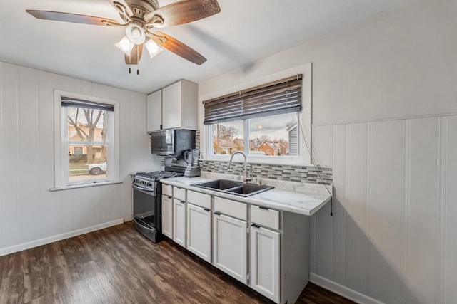 kitchen featuring dark wood finished floors, a sink, stainless steel appliances, white cabinetry, and backsplash