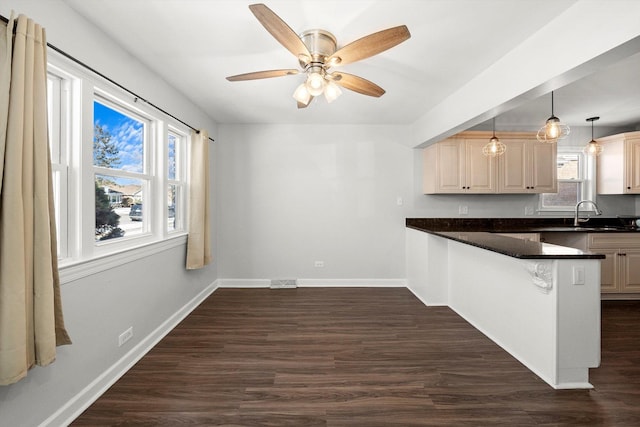 kitchen with dark countertops, dark wood-style flooring, a peninsula, and a sink