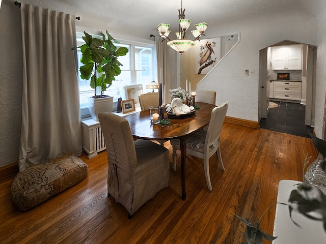 dining space featuring a notable chandelier, radiator, dark wood-style floors, and a textured wall