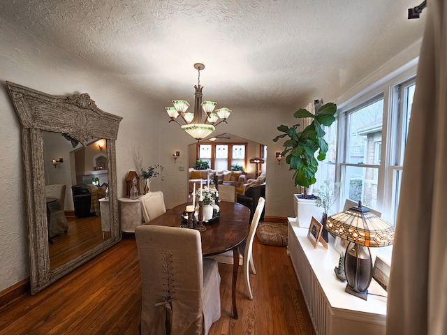 dining area with an inviting chandelier, a textured ceiling, a textured wall, and wood finished floors