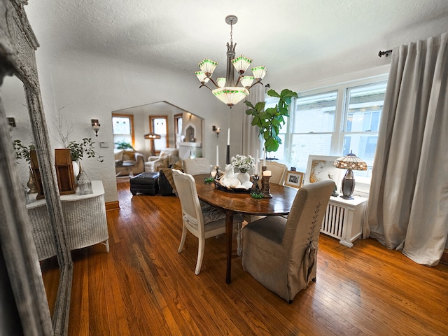 dining space with wood-type flooring, a textured ceiling, and an inviting chandelier