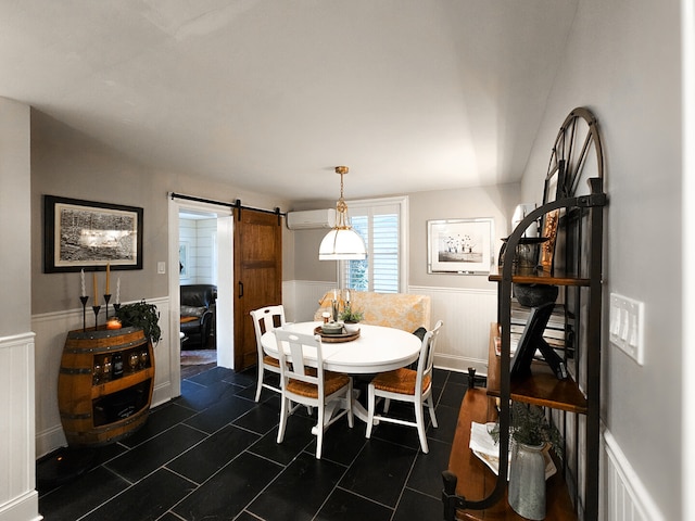 dining space with visible vents, an AC wall unit, dark tile patterned floors, a barn door, and wainscoting