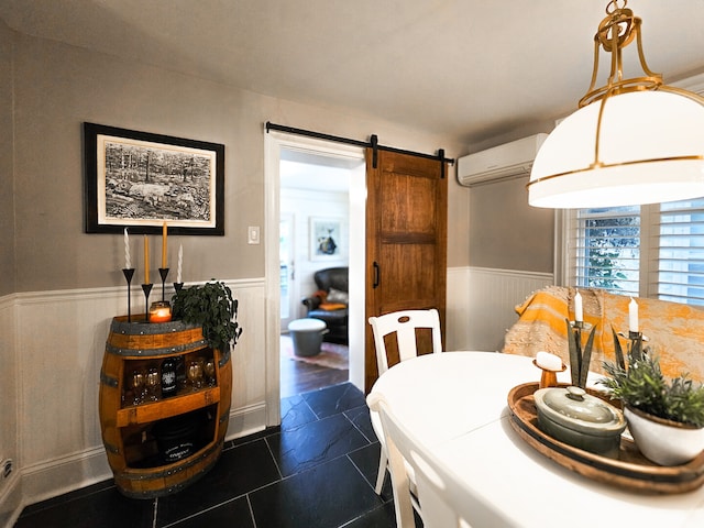 dining area with wainscoting, a wall mounted AC, and a barn door