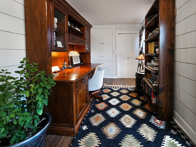 office featuring wooden walls, dark wood-style floors, and built in desk