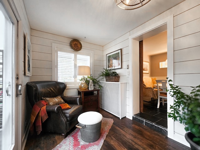 sitting room with dark wood finished floors and wood walls