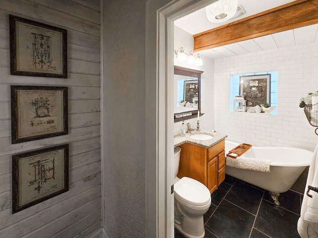 bathroom with vanity, a freestanding tub, tile walls, beamed ceiling, and toilet