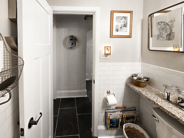 half bathroom with tile walls, toilet, and tile patterned floors